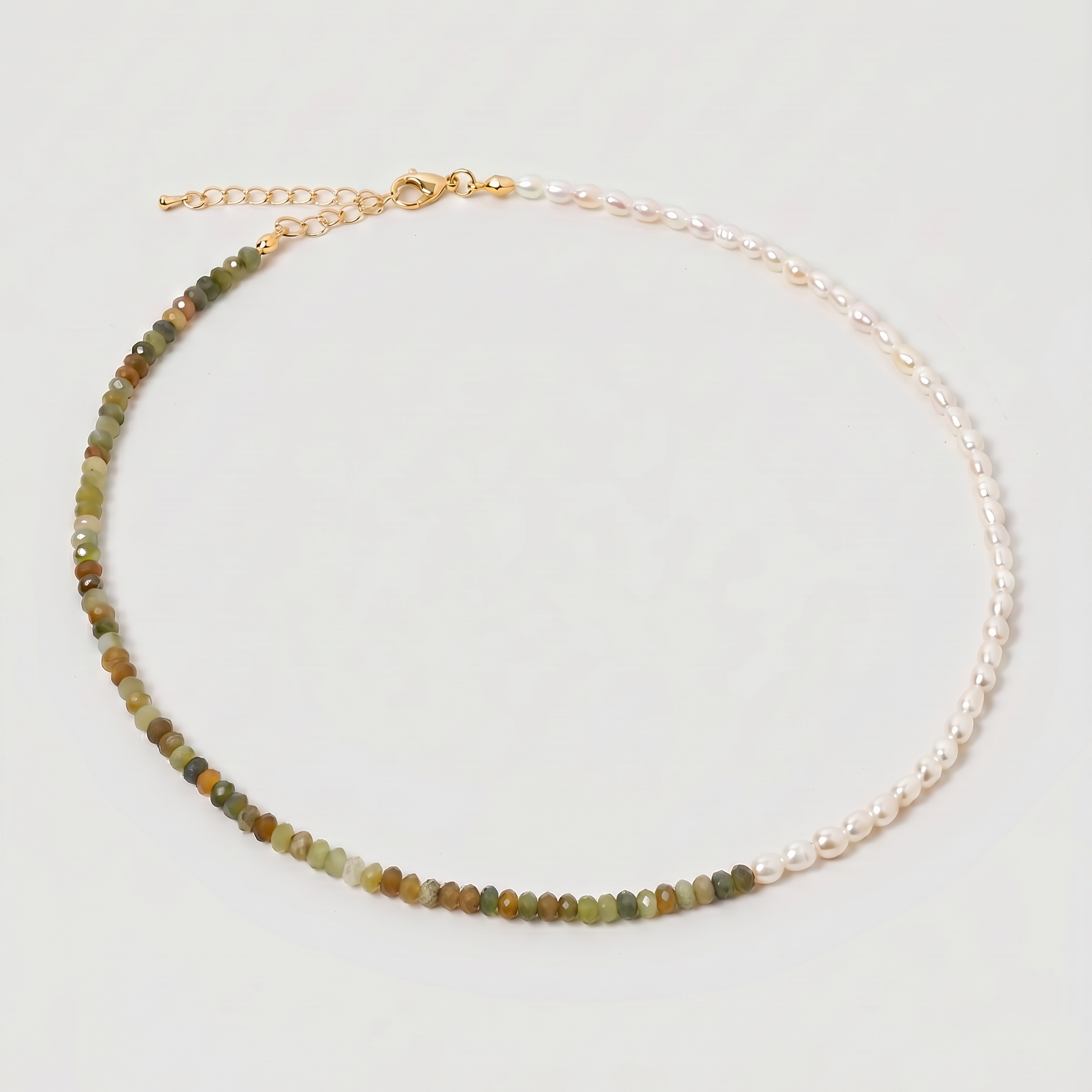 multi gemstone and pearl beaded necklace in gold, with one half strung with imitation pearl rice beads and the other half with faceted mixed quartz beads in green, sage, olive and warm brown tones, joined by a gold accent bead.
