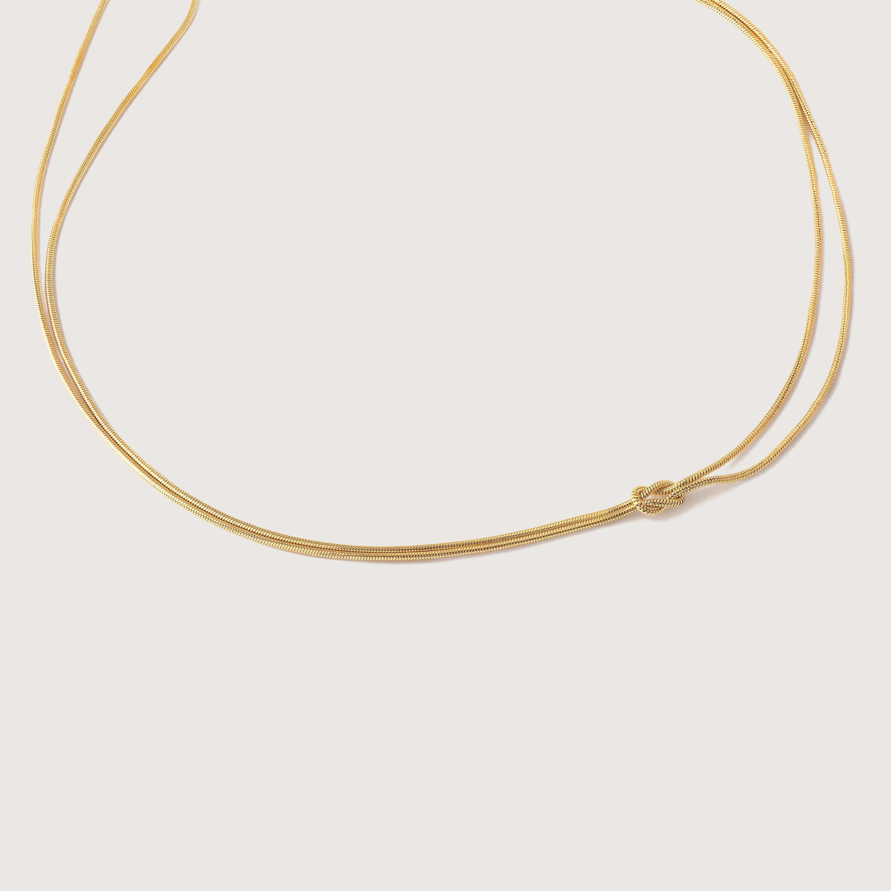 A gold-plated choker necklace with a simple infinity symbol design, featuring two loops that form a knot on one side.