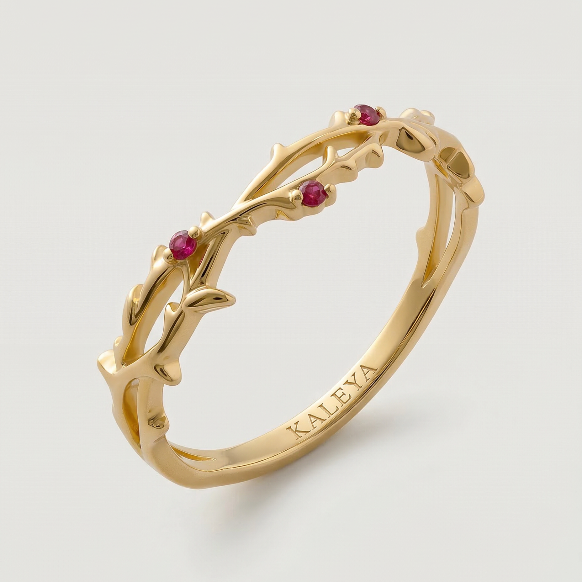 Gold ring with red gemstones on a light gray background