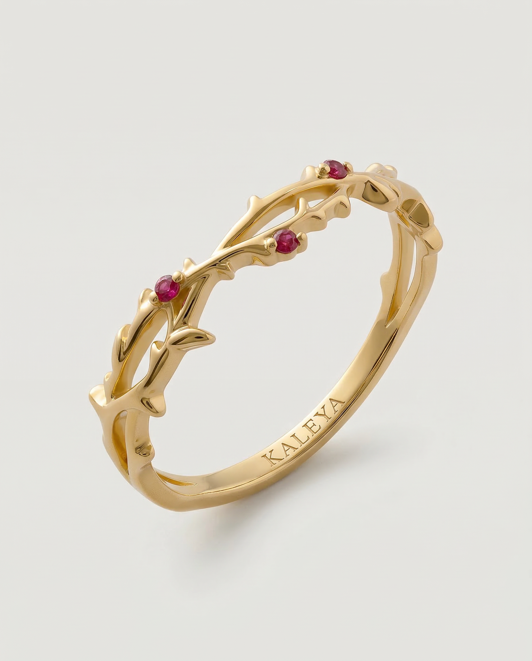 Gold ring with red gemstones on a light gray background
