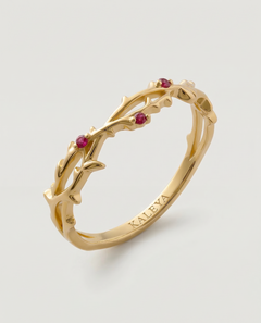 Gold ring with red gemstones on a light gray background
