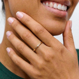 model wearing a gold-colored band ring with a single sparkling stone