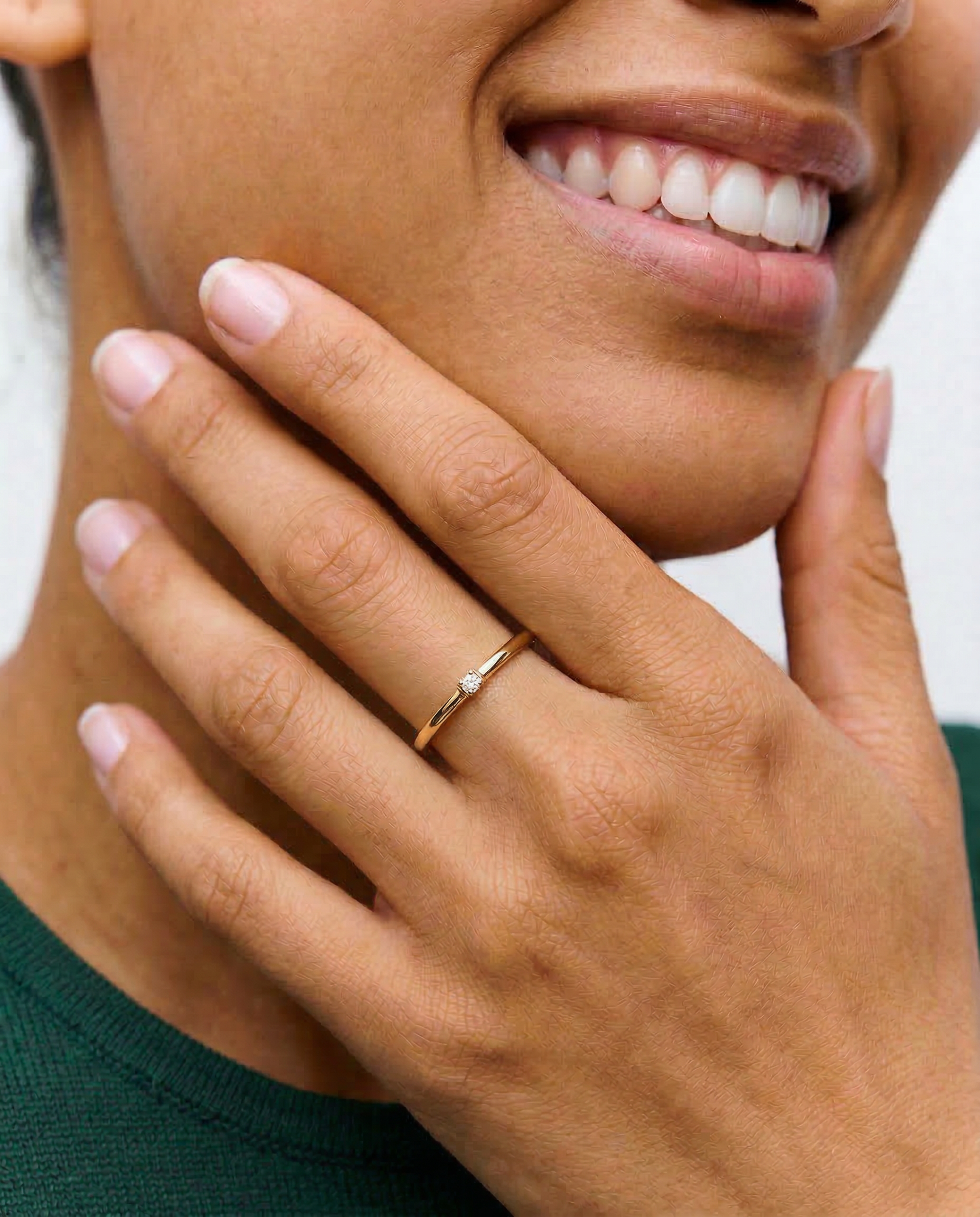 model wearing a gold-colored band ring with a single sparkling stone