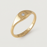 A gold signet ring with a small star-set crystal on the top, displayed against a white background.