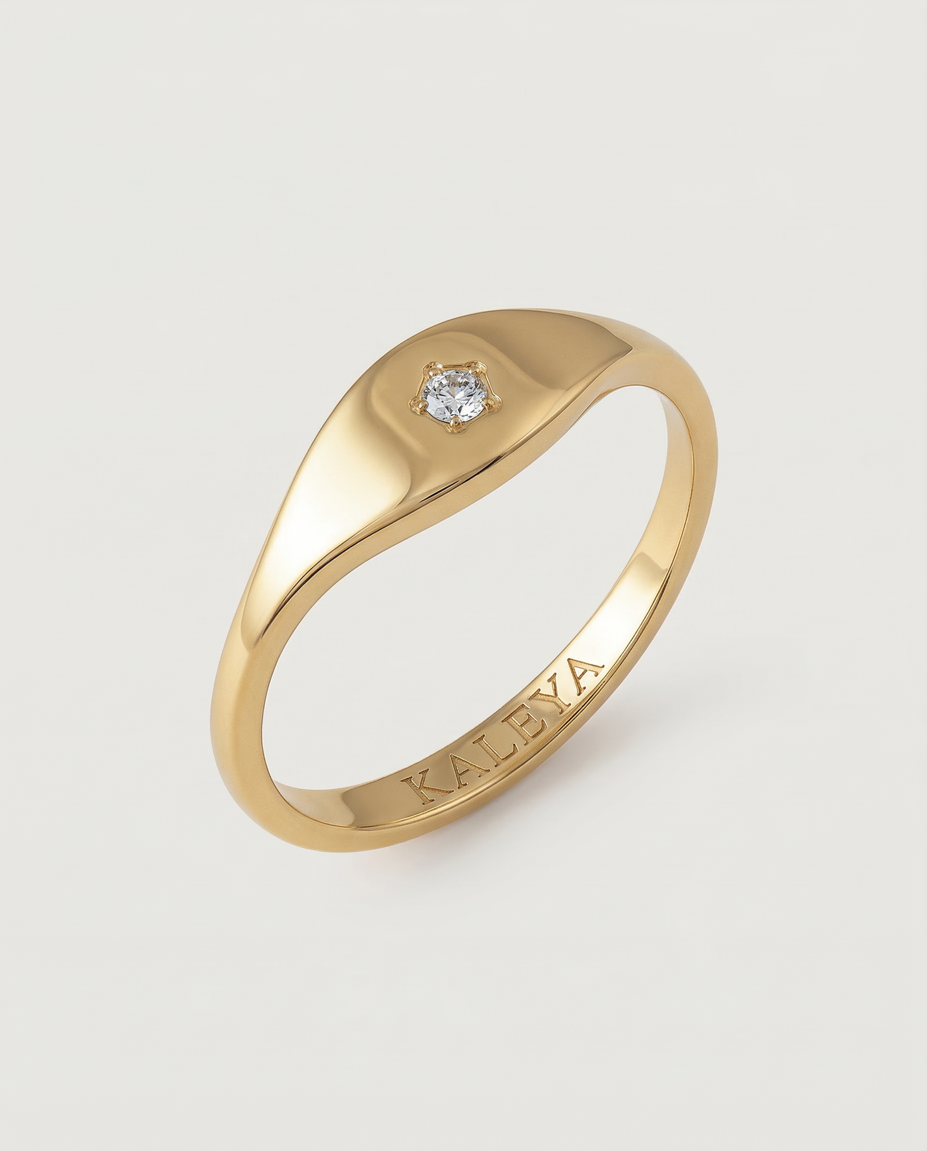 A gold signet ring with a small star-set crystal on the top, displayed against a white background.