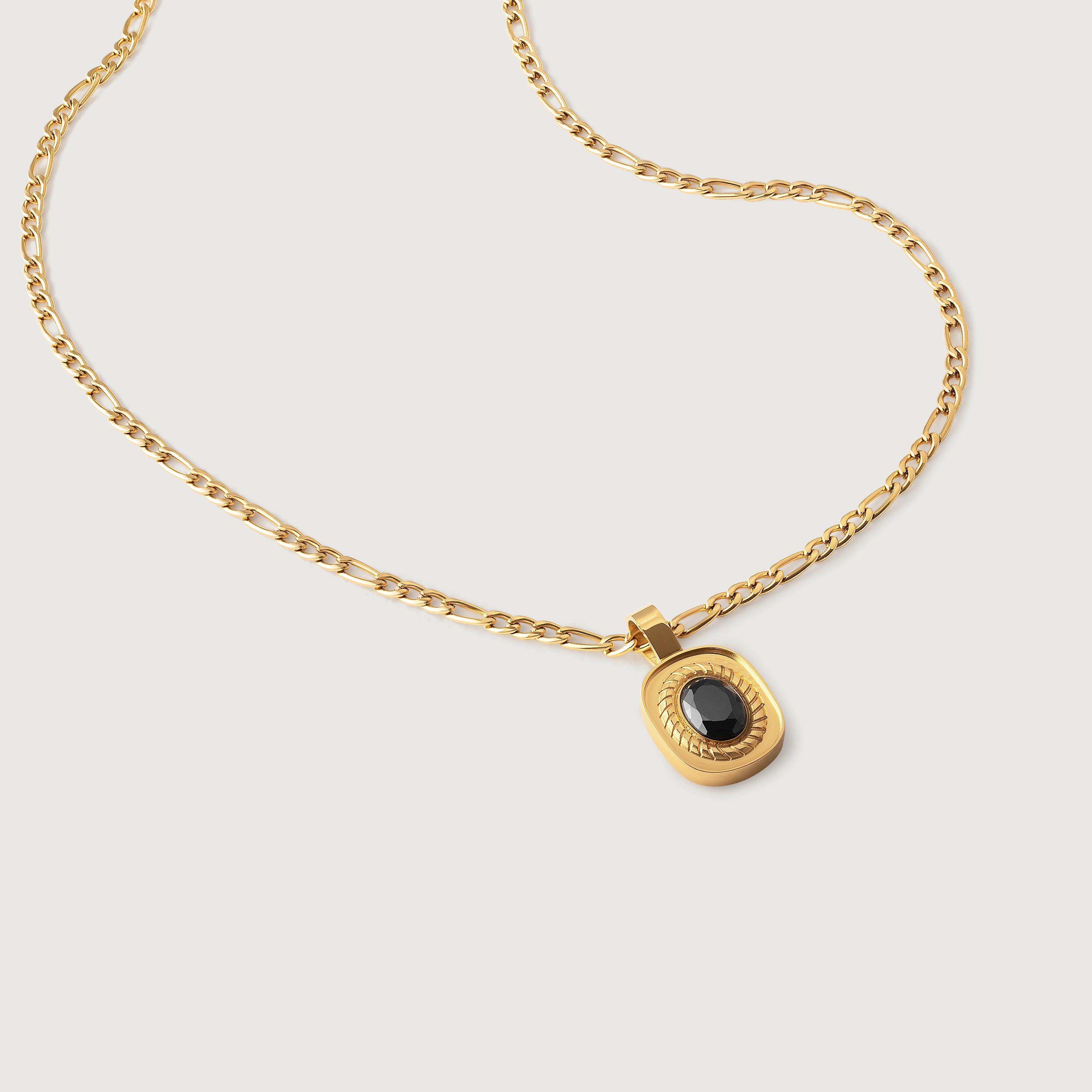 An 18k gold-plated stainless steel necklace with a polished Figaro chain and an oval medallion pendant featuring a deep black onyx stone.