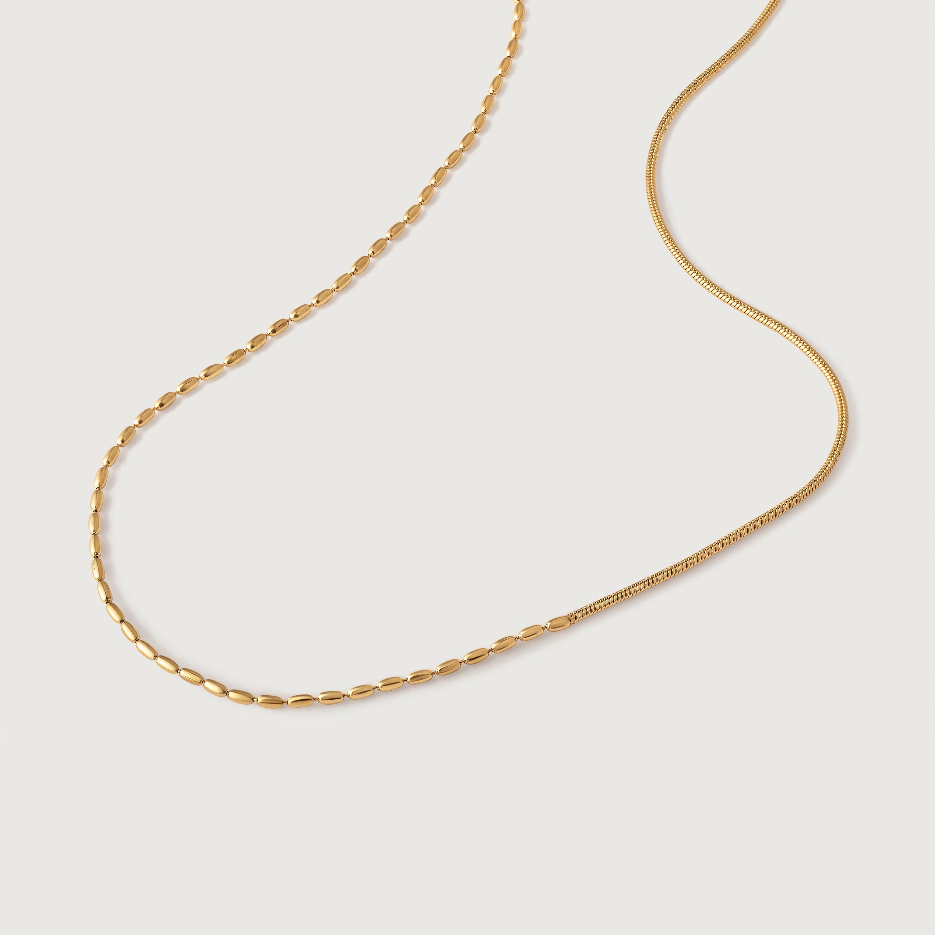 A gold-colored necklace with a chain link design, displayed against a white background.