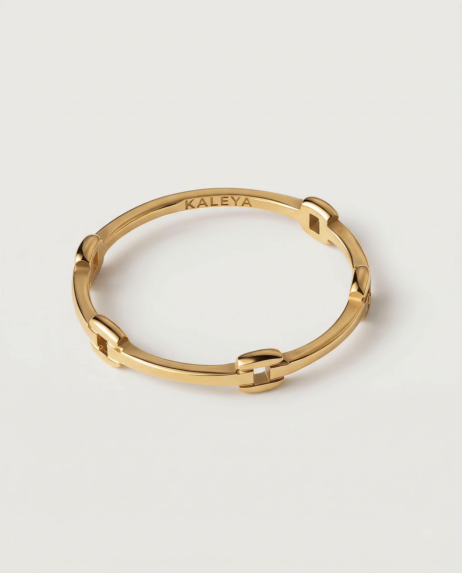 A gold-colored ring with geometric cutouts, crafted from gold-plated metal, displayed against a white background.