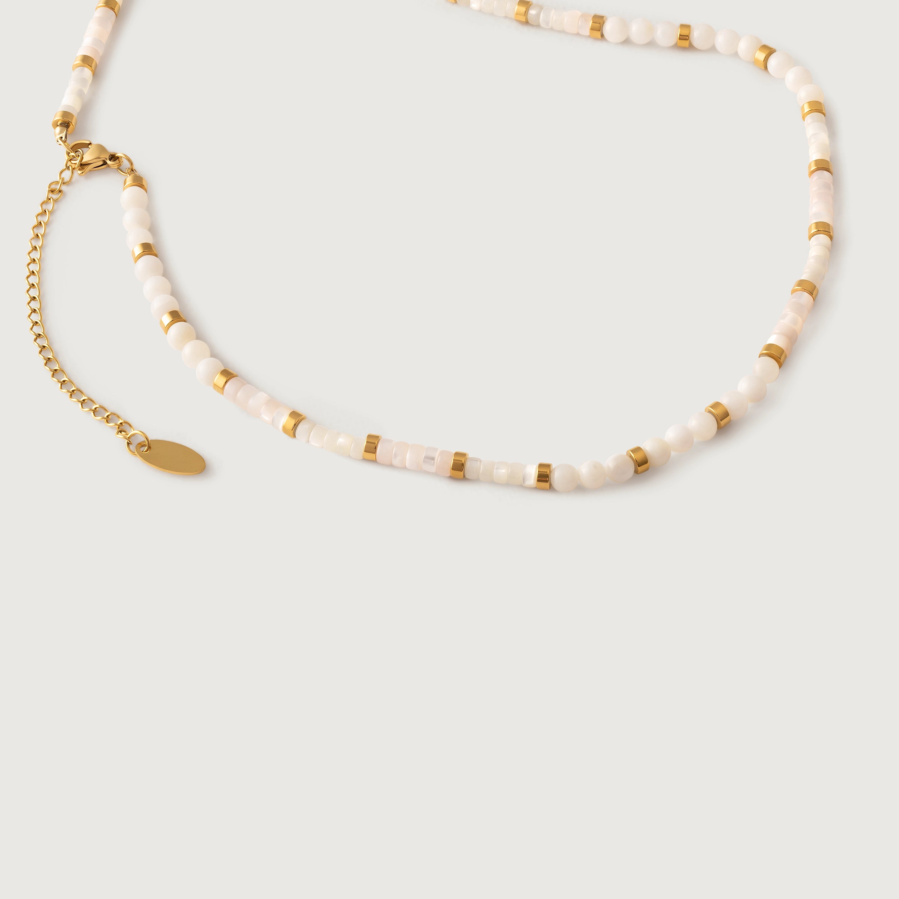 A milky white quartz bead necklace with petite metallic spacers, featuring a gold-colored chain as a choker.
