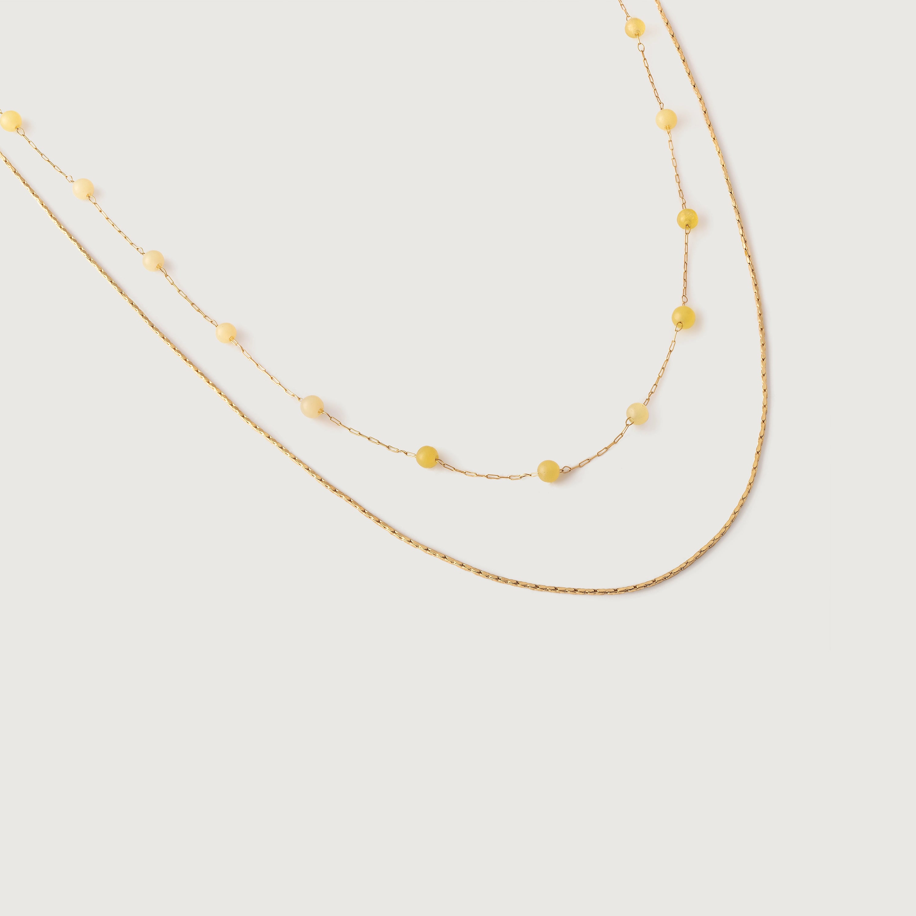 A two-tone necklace with gold links and yellow stones, displayed against a white background