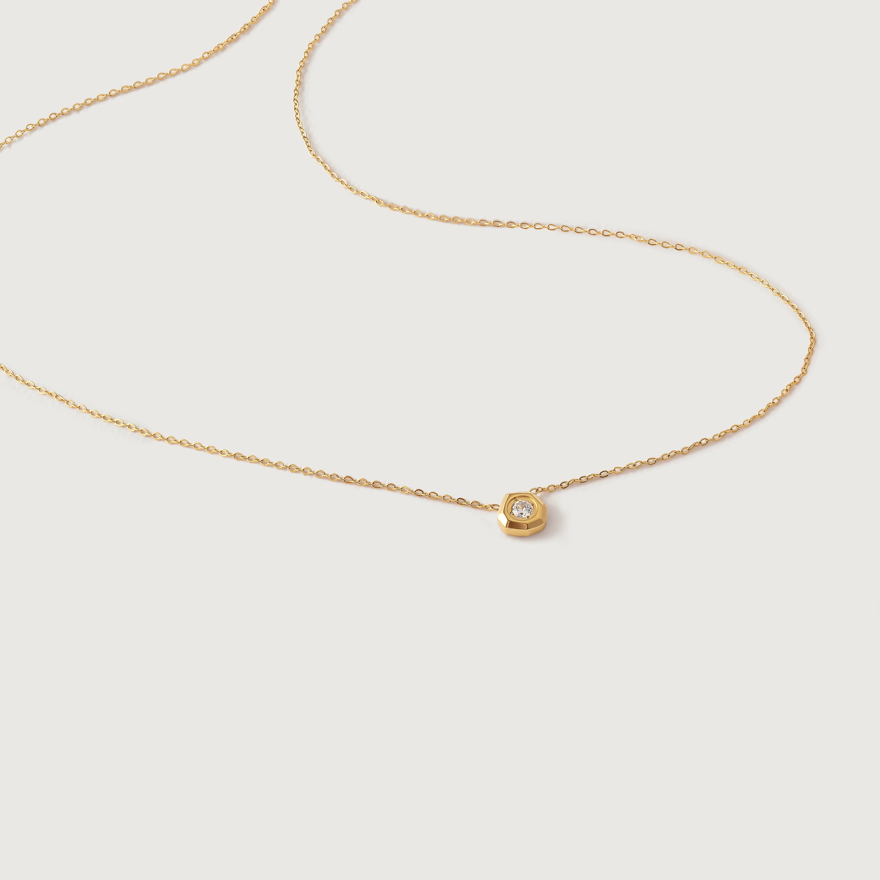 A delicate gold-plated necklace with a hexagonal setting and a single crystal pendant.