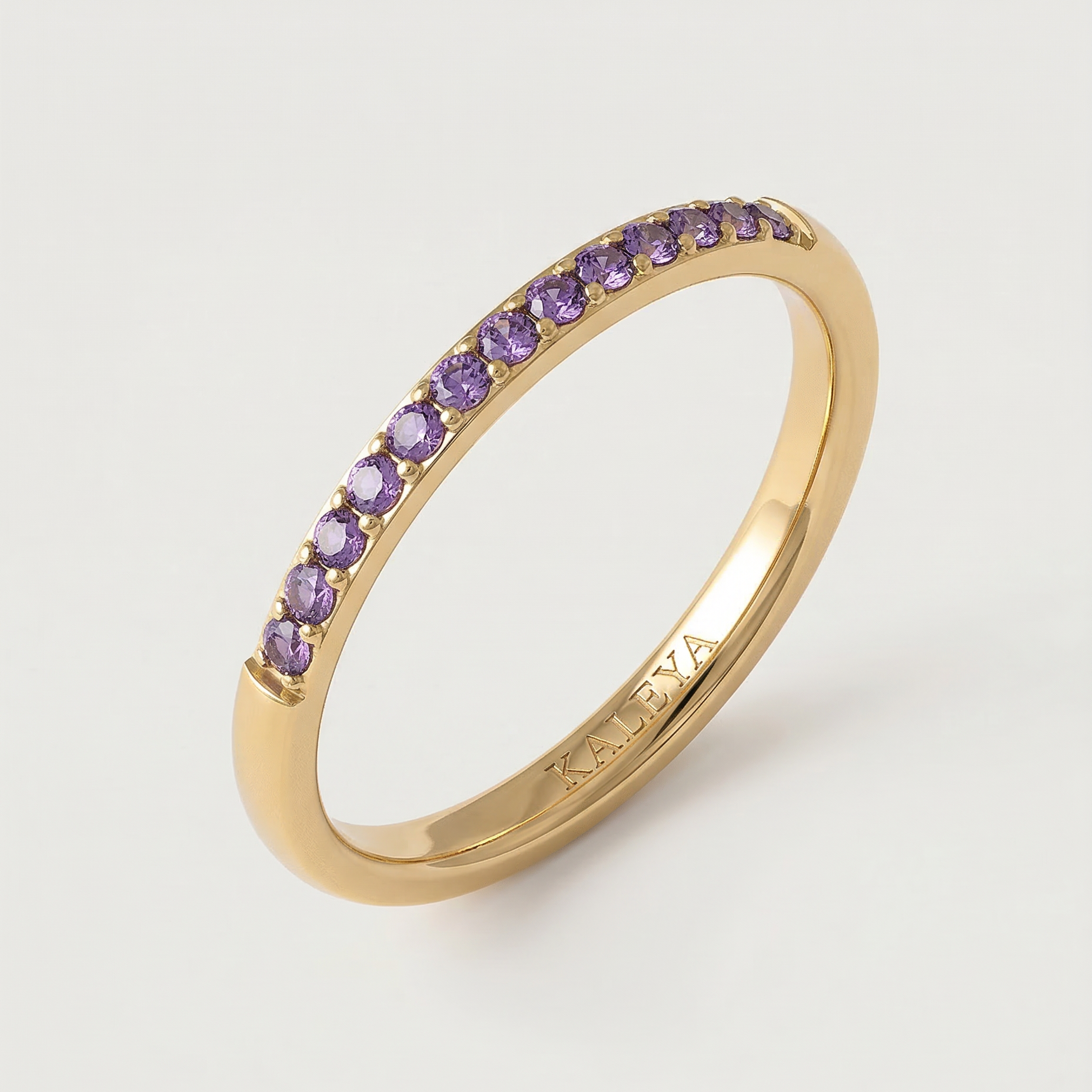 A gold-plated ring with a line of purple stones set along its circumference.