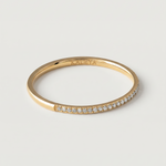A gold-plated ring with a row of sparkling cubic zirconia stones set in a pavé effect along the band.