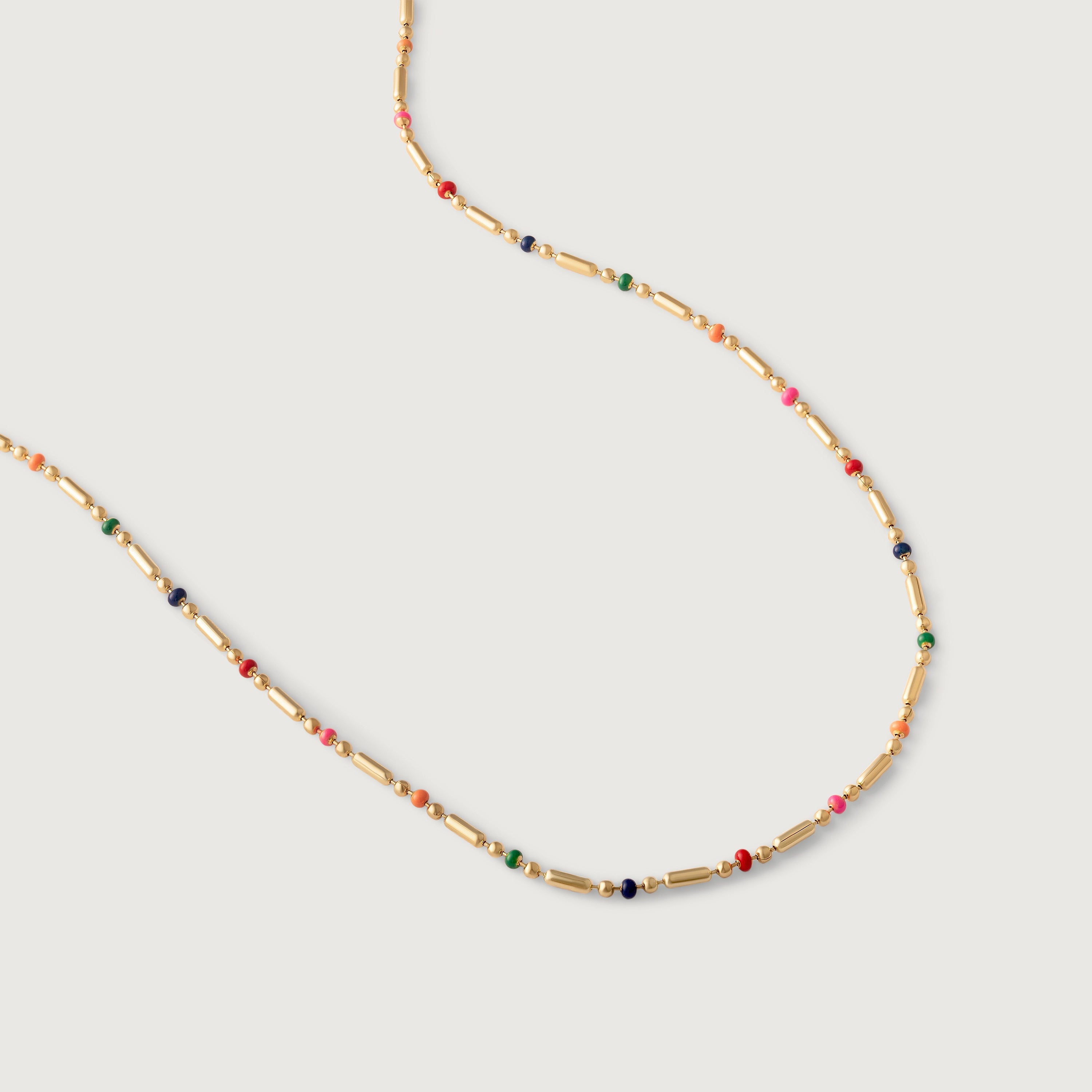 A gold-plated necklace with multicolored beads in red, pink, blue, and green, arranged in a alternating pattern between golden bars.