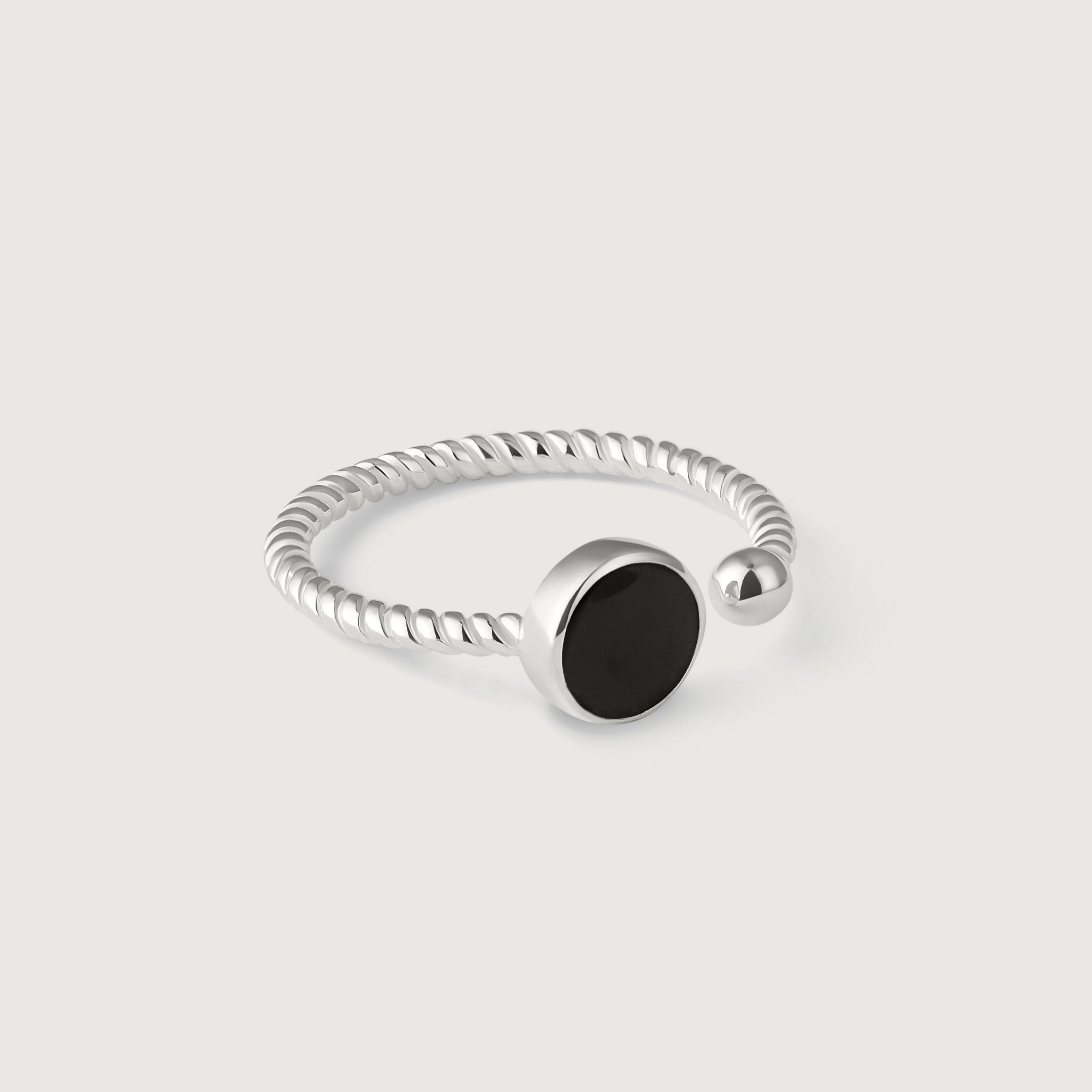 A silver ring with a twisted band and a central black onyx stone, with a small silver bead on one end.