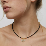 model wearing a gold-plated choker necklace with black beads and a crystal-embellished evil eye pendant