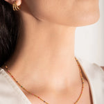 close up of a model wearing a gold-plated necklace with multicolored beads and gold bars