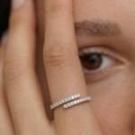 Close-up of a hand wearing a silver ring with an open spiral design adorned with sparkling cubic zirconia stones