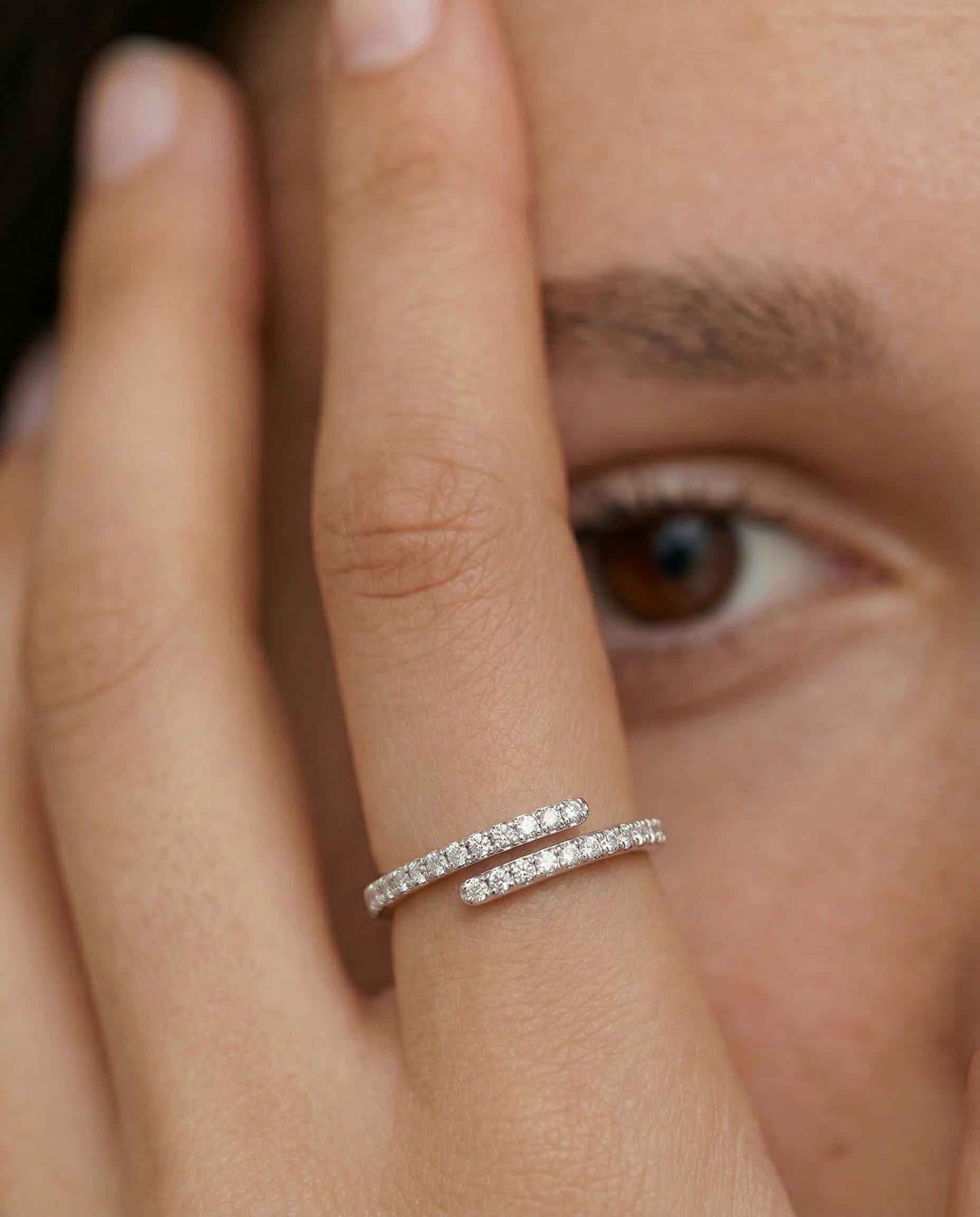Close-up of a hand wearing a silver ring with an open spiral design adorned with sparkling cubic zirconia stones