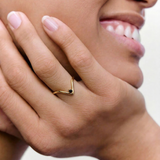 closeup of a model wearing a gold-plated ring with an angular design and a black crystal set in a V-formation