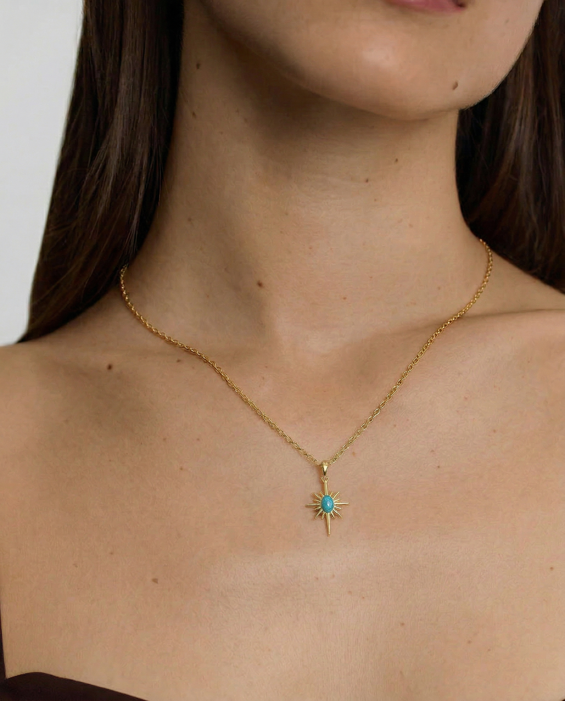 Gold necklace with a star-shaped pendant worn by a person
