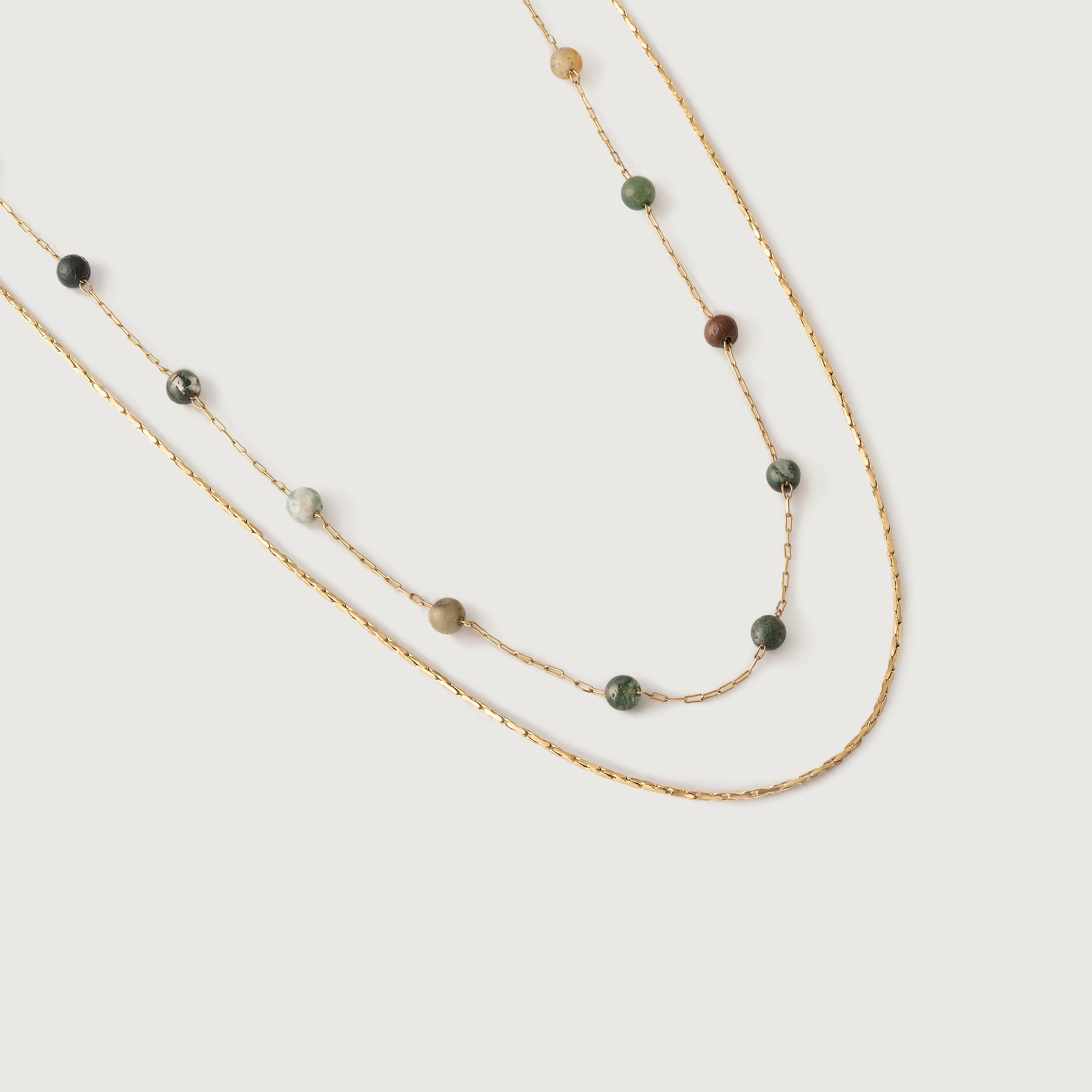 A two-tiered necklace with fine gold chains and forest-hued jasper beads, displayed against a white background.