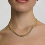 close up of a female wearing a gold-plated mesh necklace with a fluid ribbon design