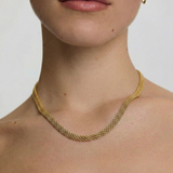 close up of a female wearing a gold-plated mesh necklace with a fluid ribbon design