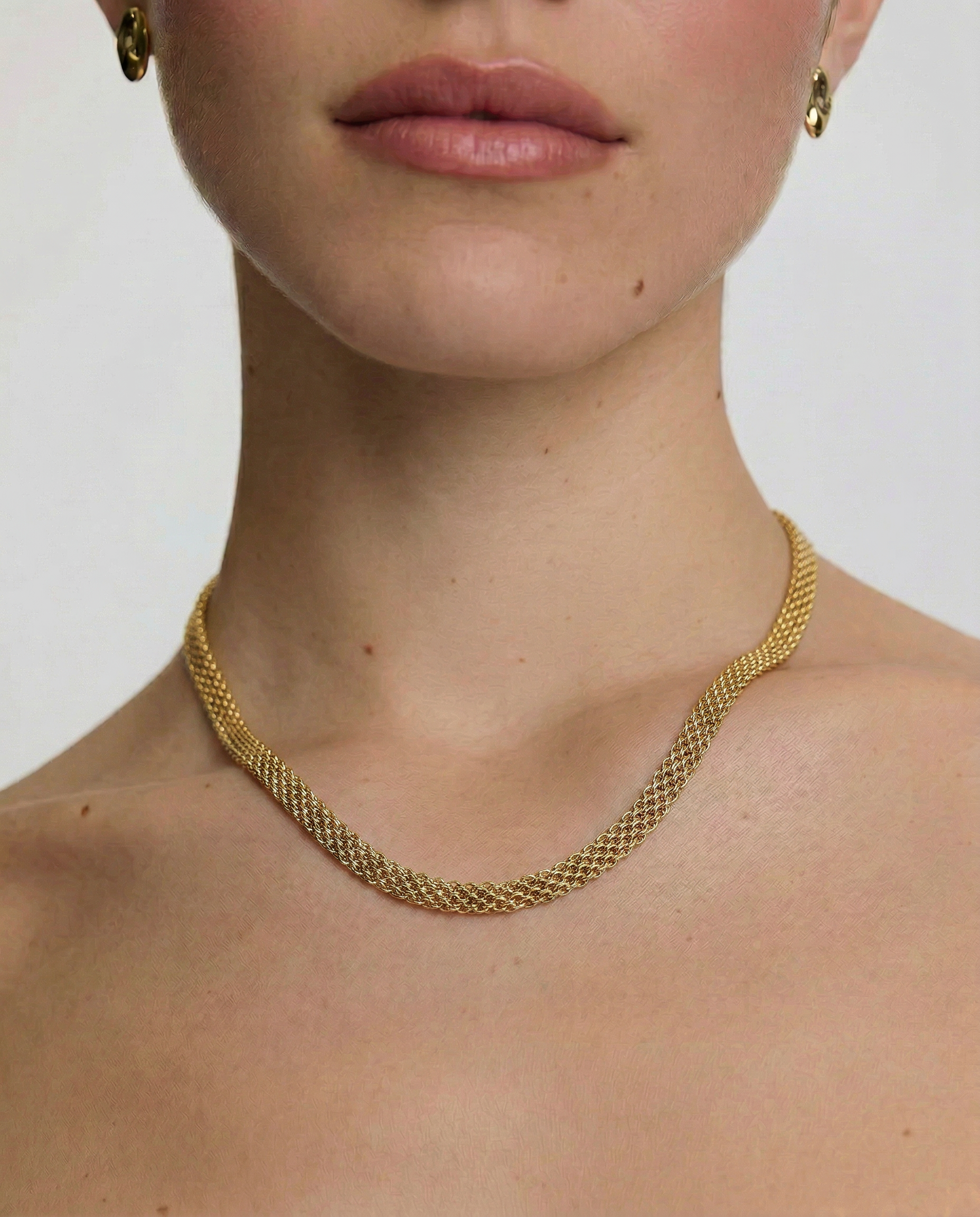 close up of a female wearing a gold-plated mesh necklace with a fluid ribbon design