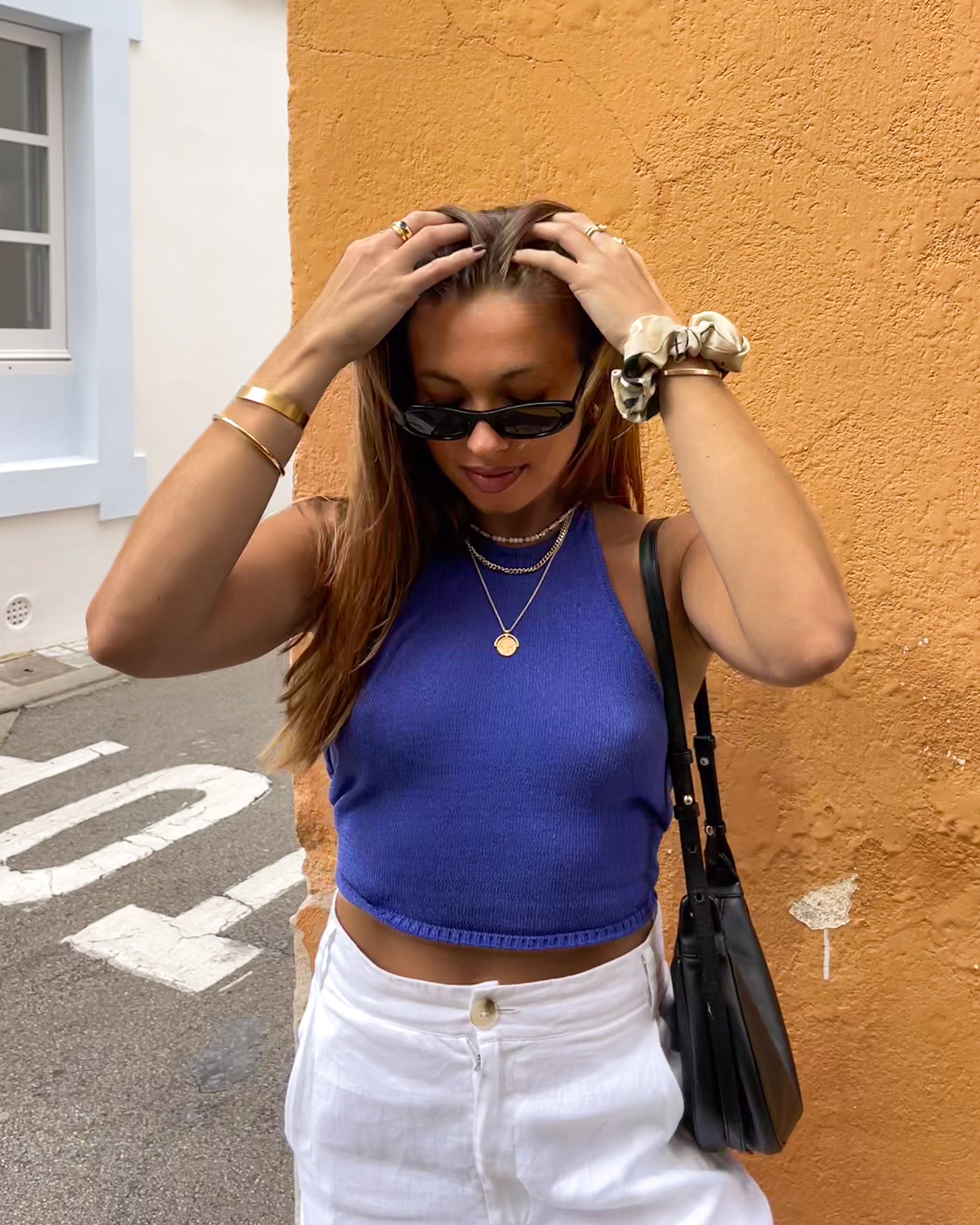 Woman in blue top and white pants wearing multiple Kaleya studio jewellery products