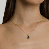 model wearing a gold-plated pendant necklace with a black crystal set in a sunburst frame