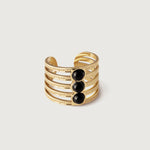 A gold-plated cuff ring with five bands and three onyx stones in the center, presented against a white background.