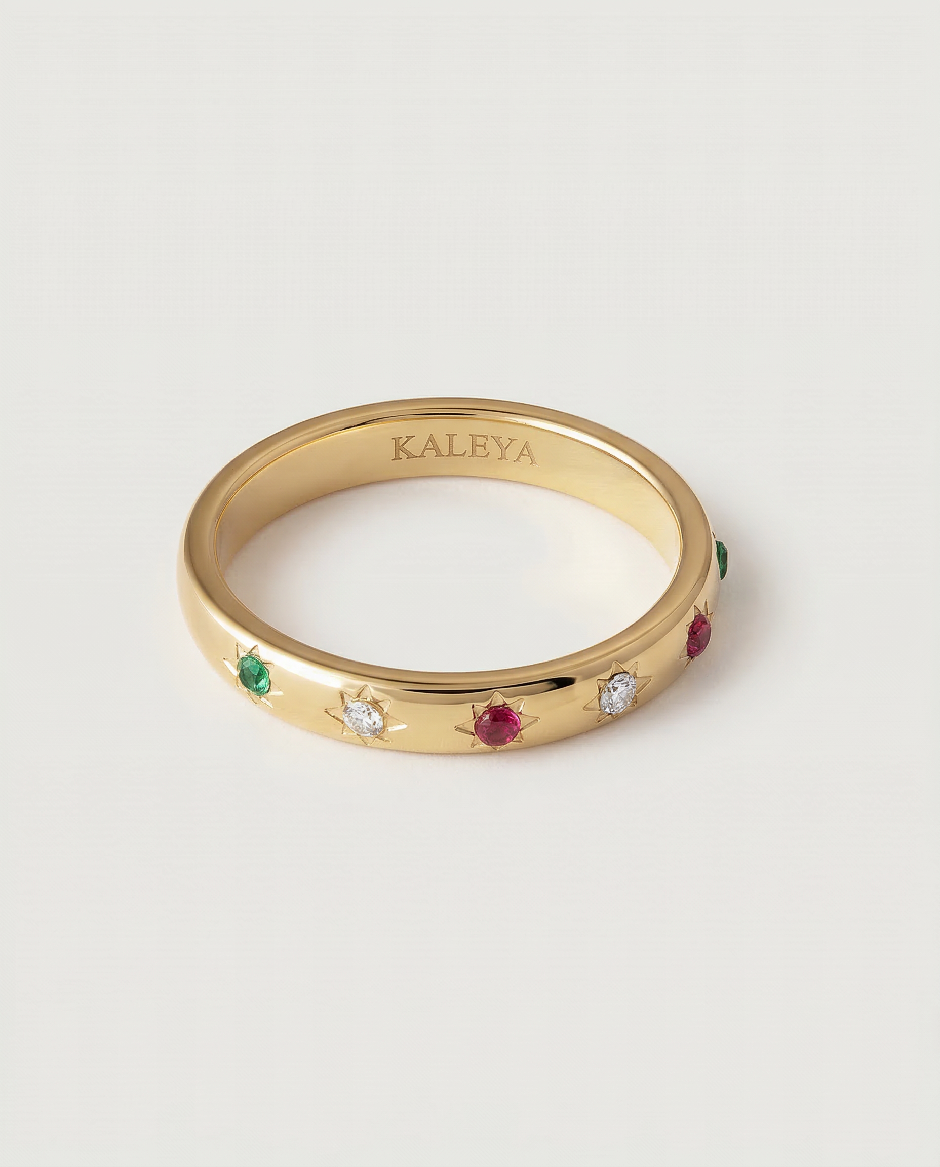 A gold-plated ring with a series of vibrant gemstones set in star-shaped bezels along the polished band.