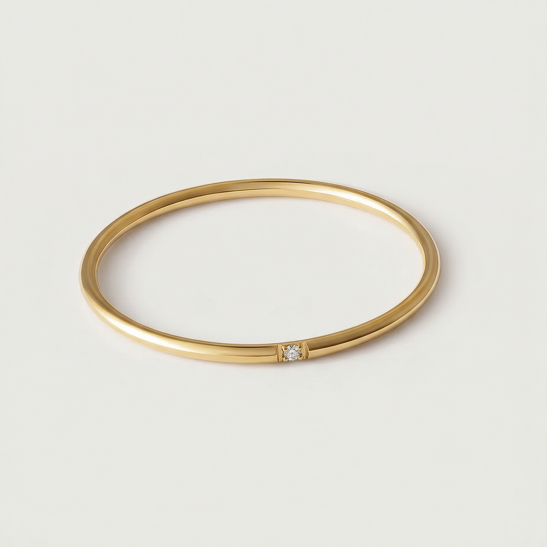 A gold-colored band ring with a single sparkling stone on a white background.