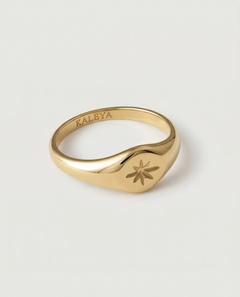 A gold signet ring with a star engraving on the top, crafted from gold-plated metal.