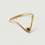 A gold-plated ring with an angular design and a black crystal set in a V-formation on a white background.