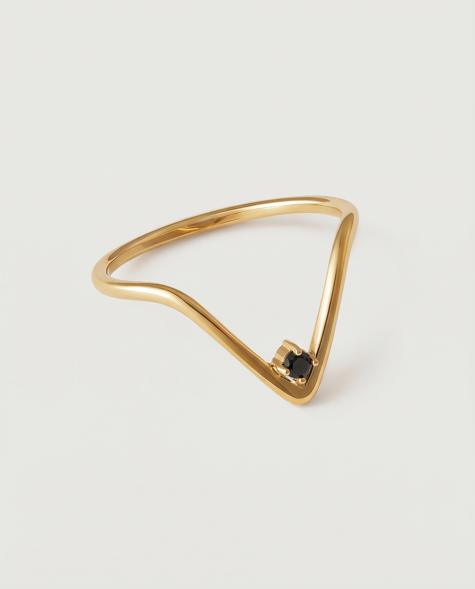 A gold-plated ring with an angular design and a black crystal set in a V-formation on a white background.
