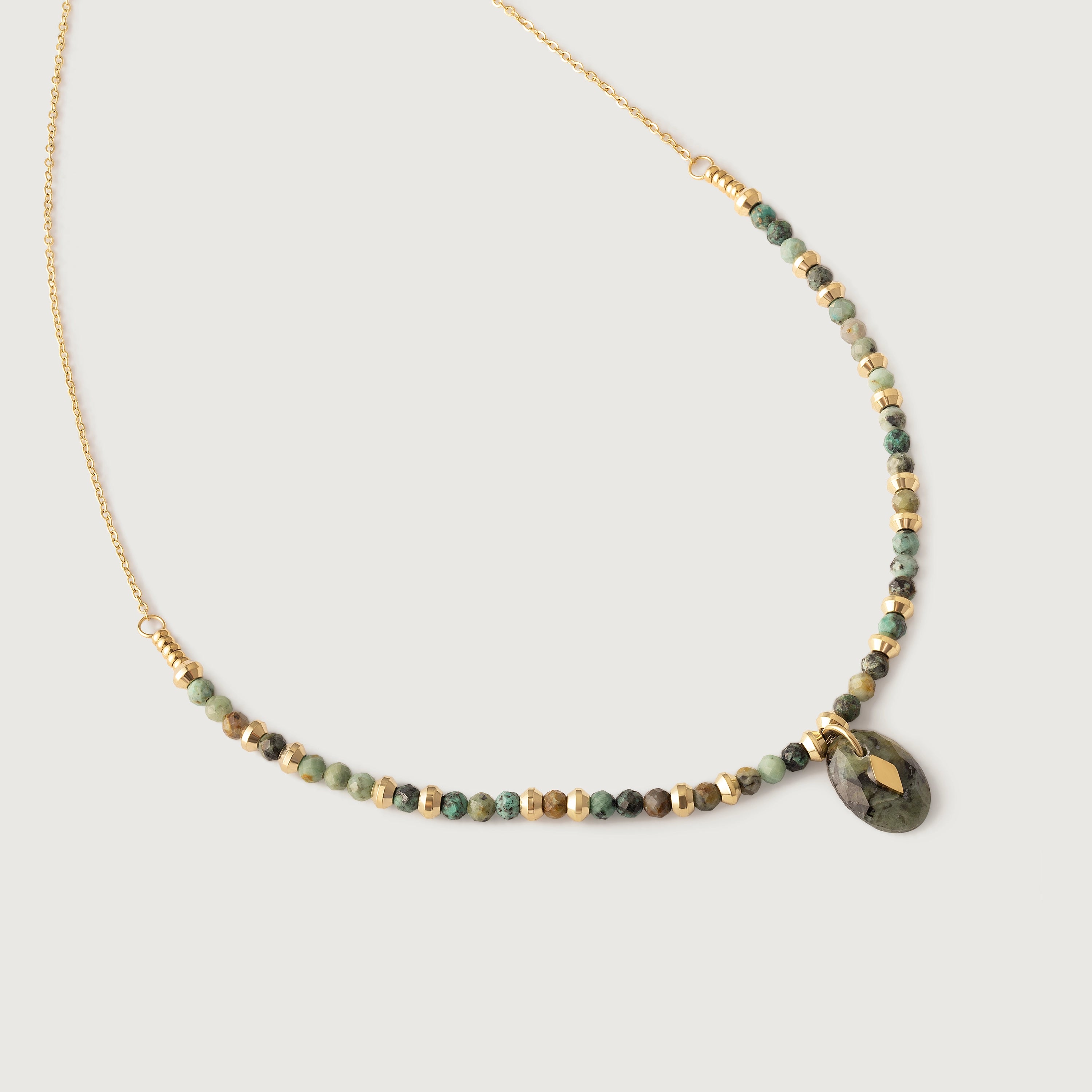 A gold-toned necklace with natural African turquoise beads in shades of sage, moss, and earth tones, featuring a smooth oval pendant.