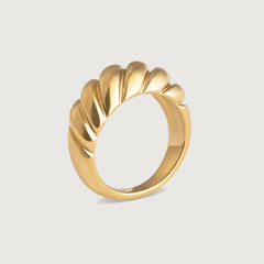 A gold-plated stainless steel ring with a textured, wave-like design on a white background.