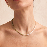 model wearing a multi gemstone and pearl beaded necklace in gold, with one half strung with imitation pearl rice beads and the other half with faceted mixed quartz beads in green, sage, olive
