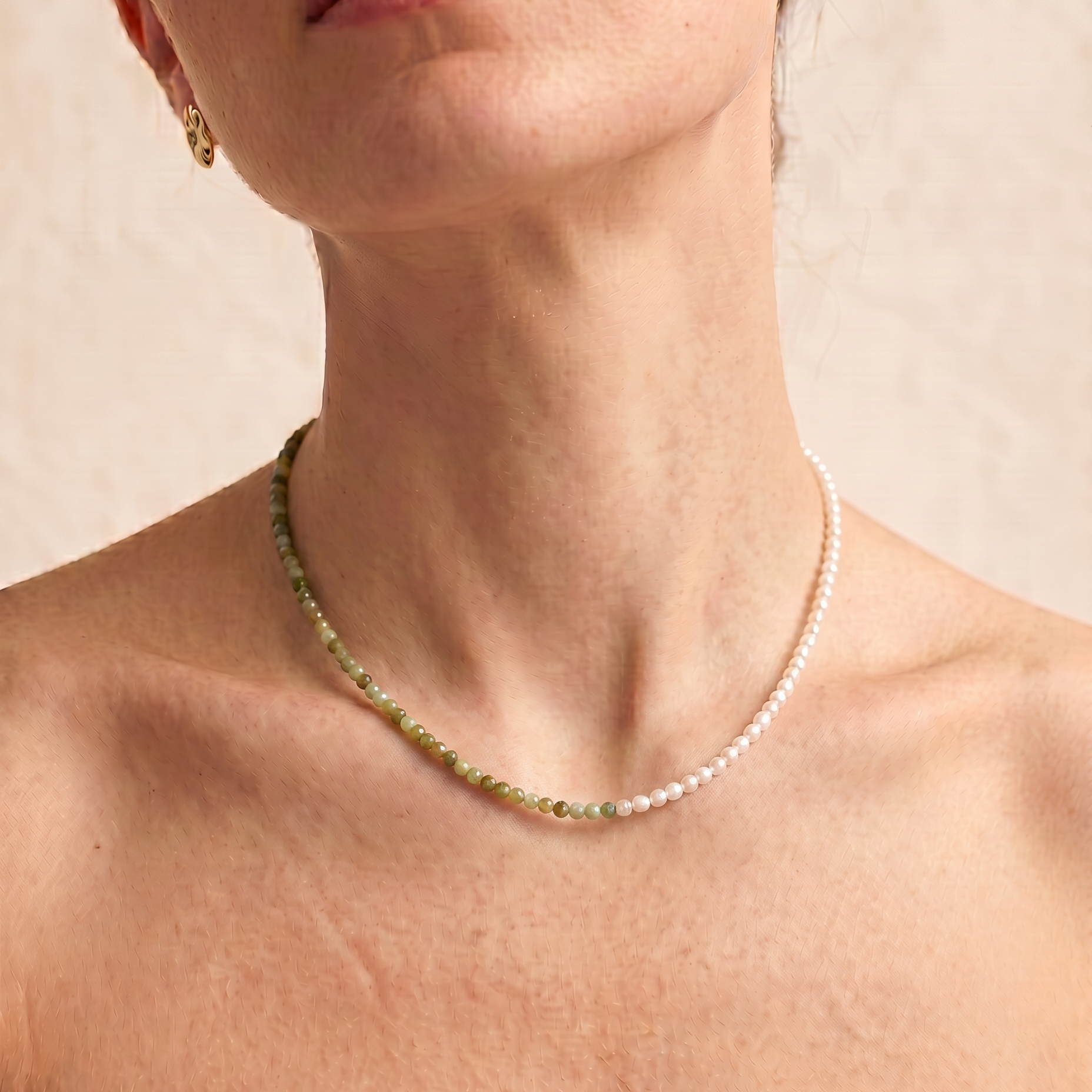 model wearing a multi gemstone and pearl beaded necklace in gold, with one half strung with imitation pearl rice beads and the other half with faceted mixed quartz beads in green, sage, olive