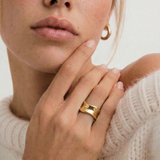 Woman wearing a gold ring on her finger with a neutral background