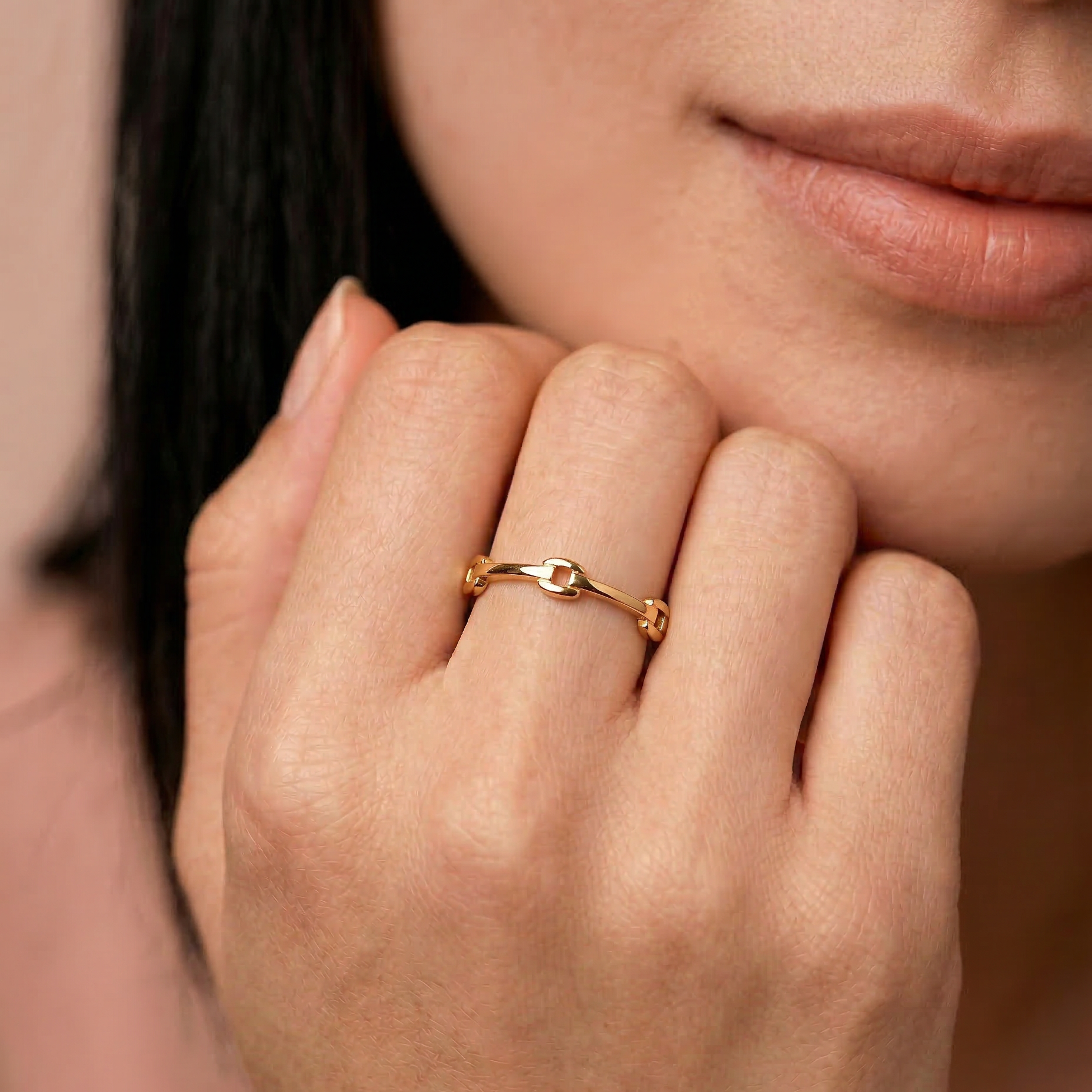 model wearing a gold-colored ring with geometric cutouts, crafted from gold-plated metal, displayed against a white background.
