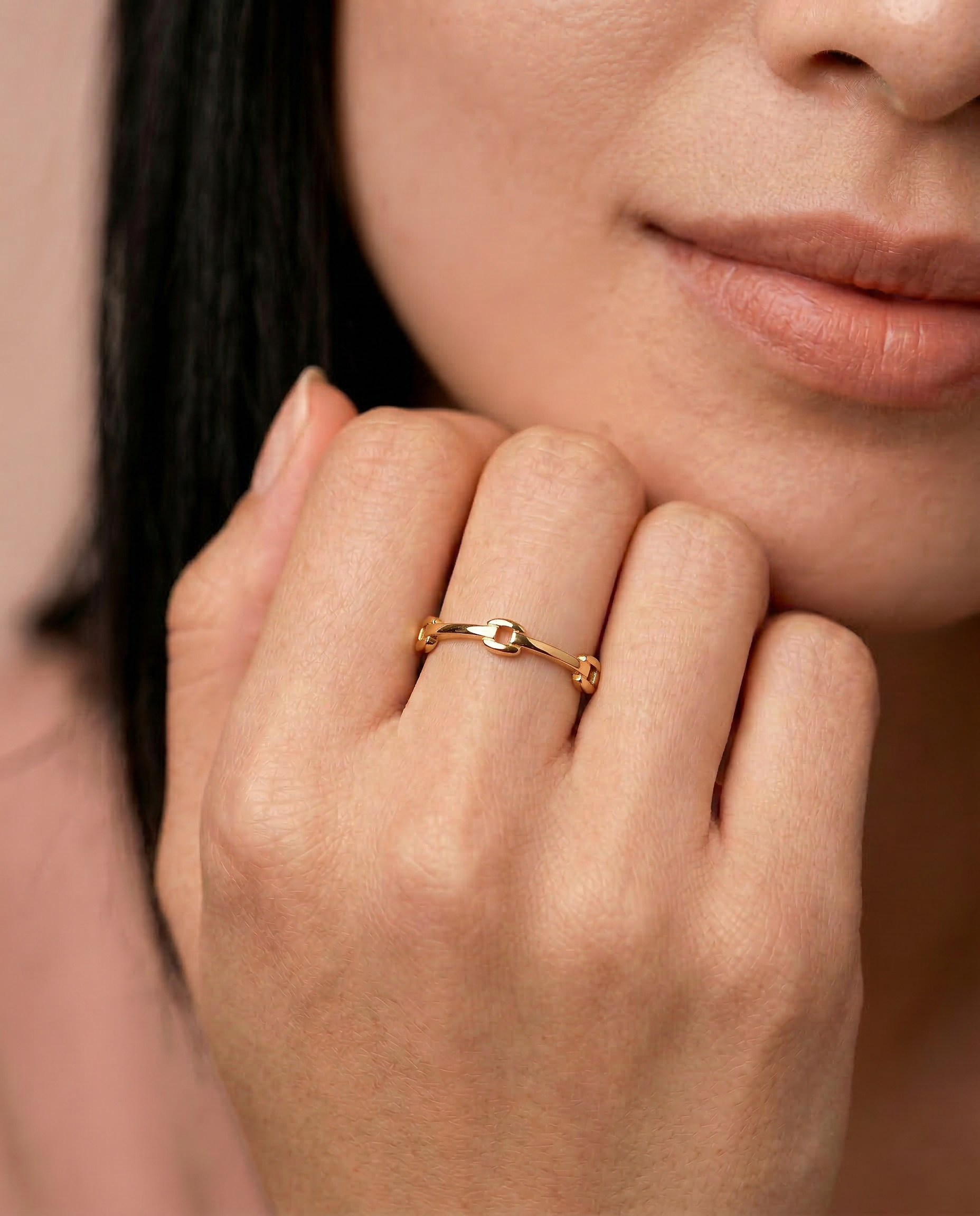 model wearing a gold-colored ring with geometric cutouts, crafted from gold-plated metal, displayed against a white background.