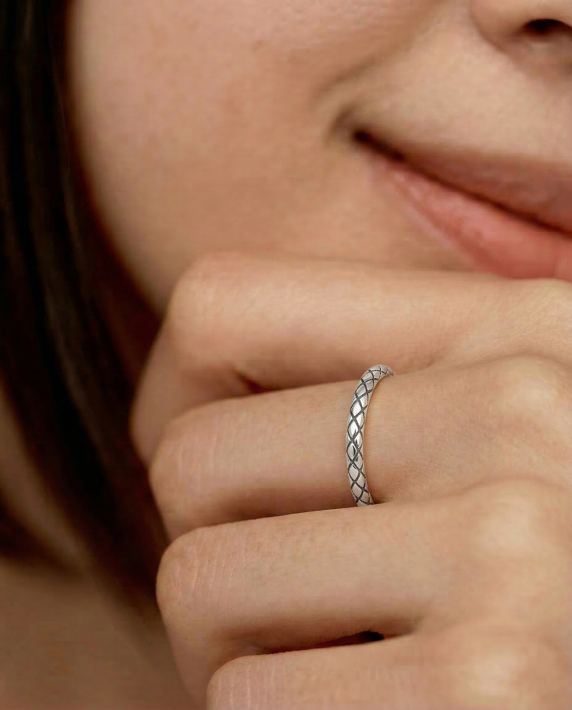 model wearing a sterling silver ring with an intricate scale-like pattern