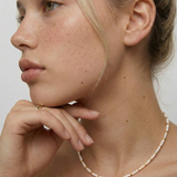 model wearing a milky white quartz bead necklace with petite metallic spacers, featuring a gold-colored chain as a choker.
