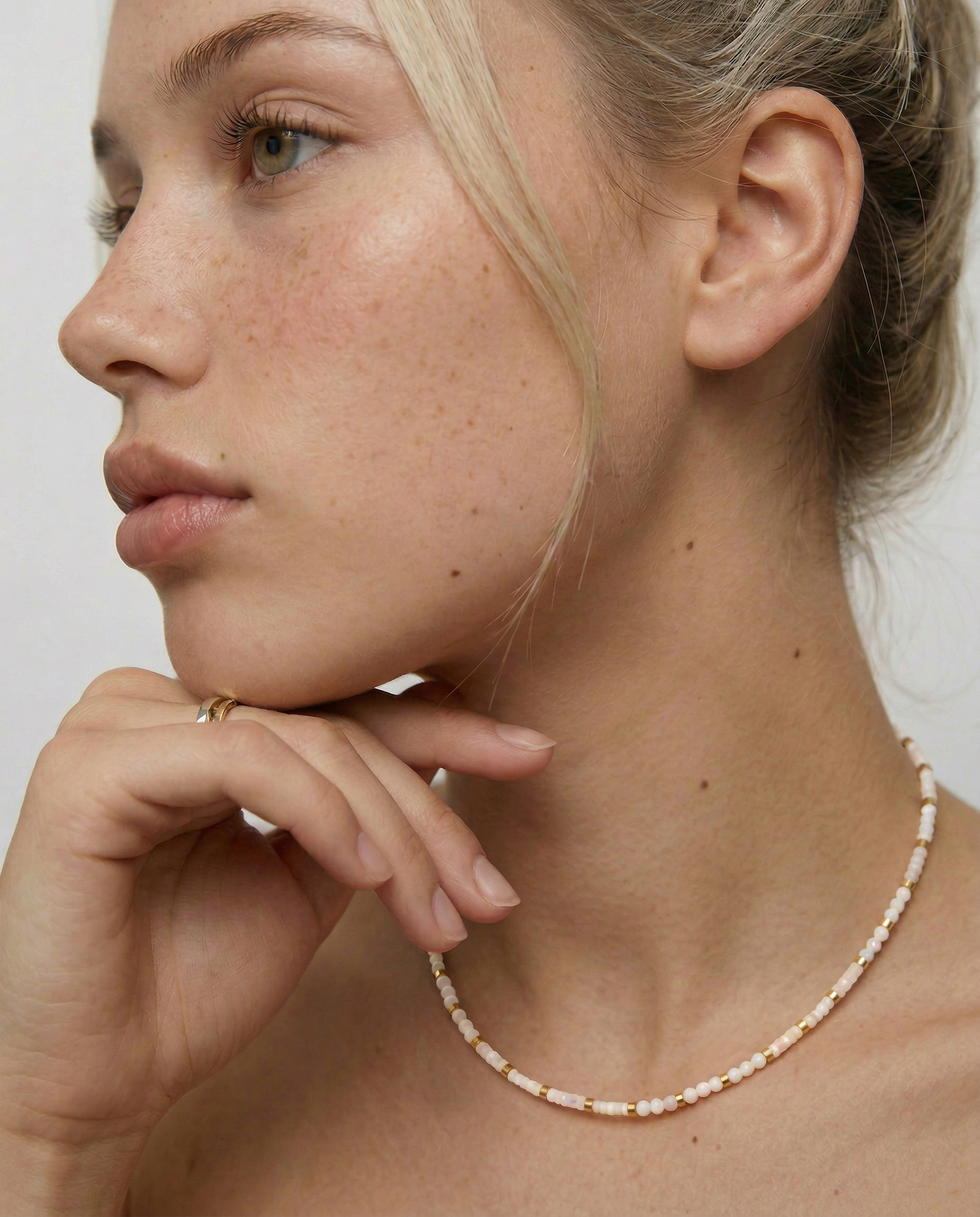 model wearing a milky white quartz bead necklace with petite metallic spacers, featuring a gold-colored chain as a choker.