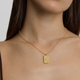 model wearing a gold plated necklace with a pendant saying "you are loved" in rainbow letters