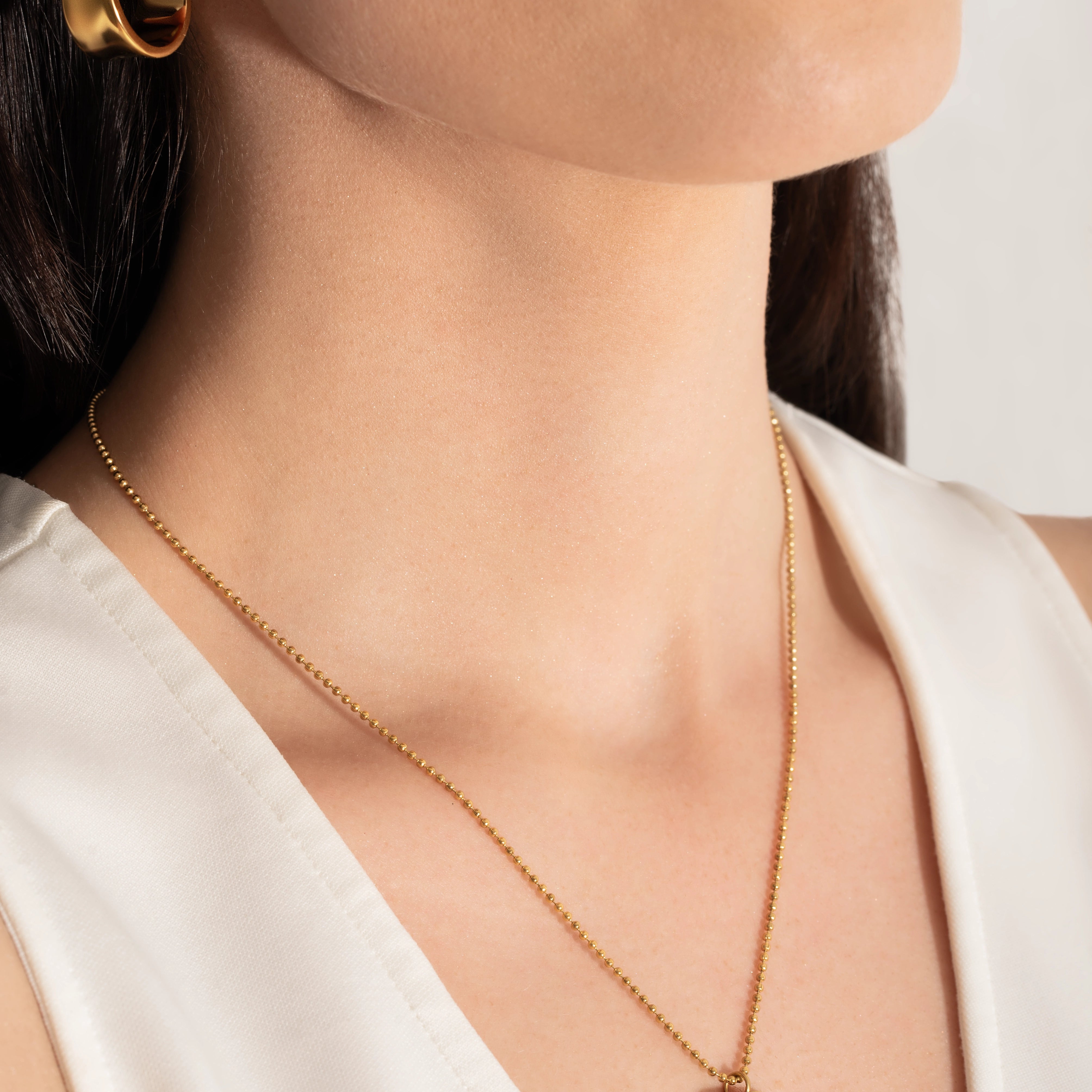 close up of a model wearing a gold-plated necklace with a pendant featuring the phrase 'you are loved' 