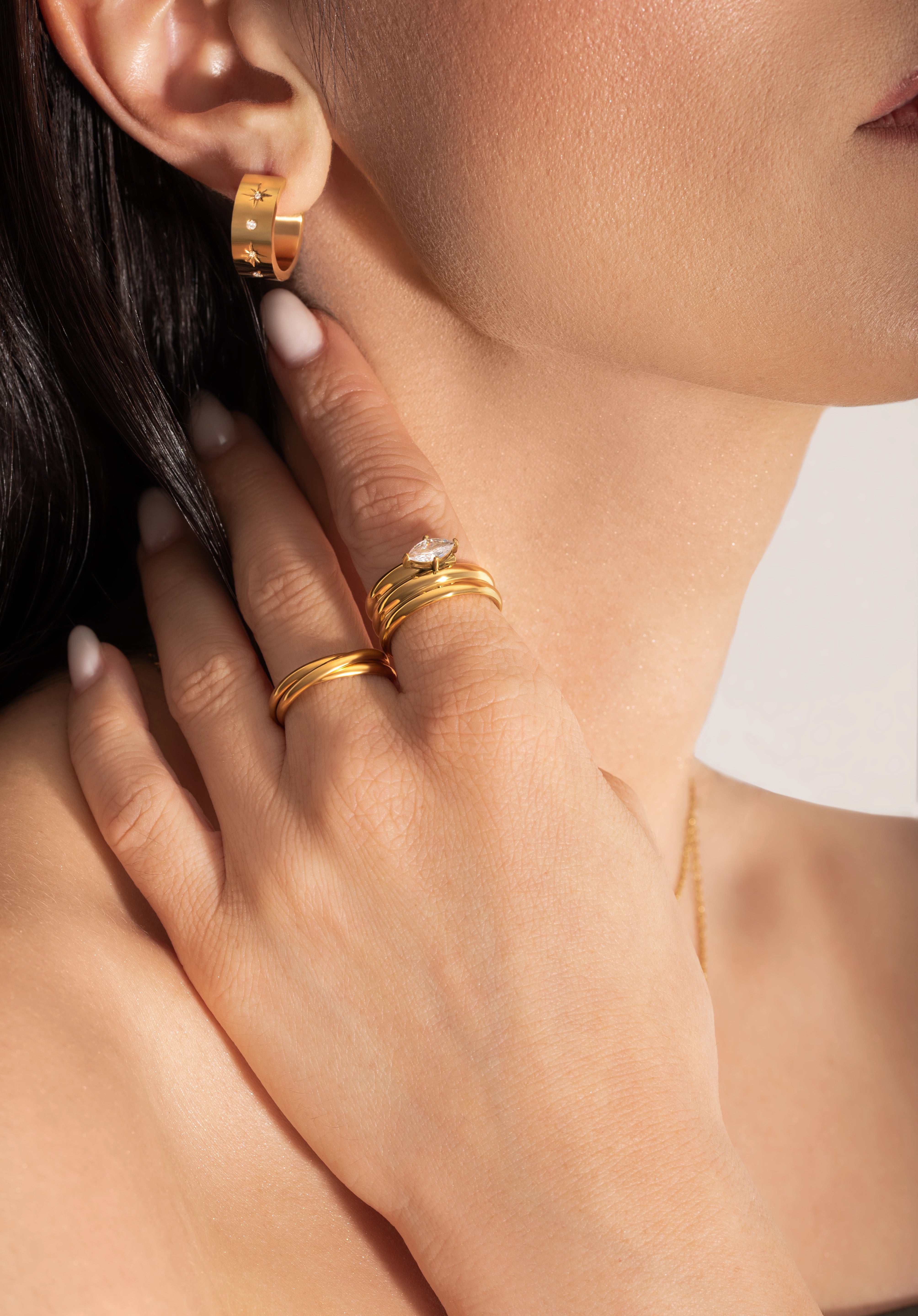 close up of a female model wearing bold statement gold plated ring with big zirconia stone and earrings